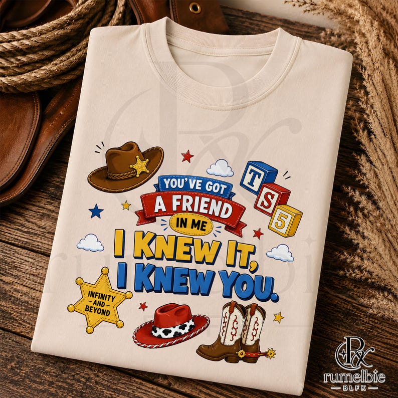 Puede incluir: Una camiseta beige con un estampado gr&aacute;fico que incluye un sombrero de vaquero marr&oacute;n, un sombrero rojo y blanco con estampado de vaca y botas de vaquero marrones. El texto dice: You've got a friend in me, I knew it, I knew you, Infinity and Beyond y TS5, con iconos de estrellas.