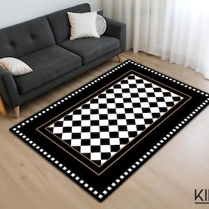 Può includere: Un tappeto rettangolare a scacchi bianchi e neri, con un bordo nero e un bordo interno dorato. Il tappeto è posato su un pavimento in legno chiaro. Sullo sfondo un divano grigio scuro con cuscini e una coperta gialla.
