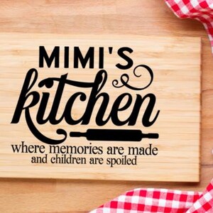May include: A rectangular wooden cutting board with the words "MIMI'S kitchen" in black script. Below the text is a rolling pin graphic and the phrase "where memories are made and children are spoiled." A red and white checkered cloth is in the background.