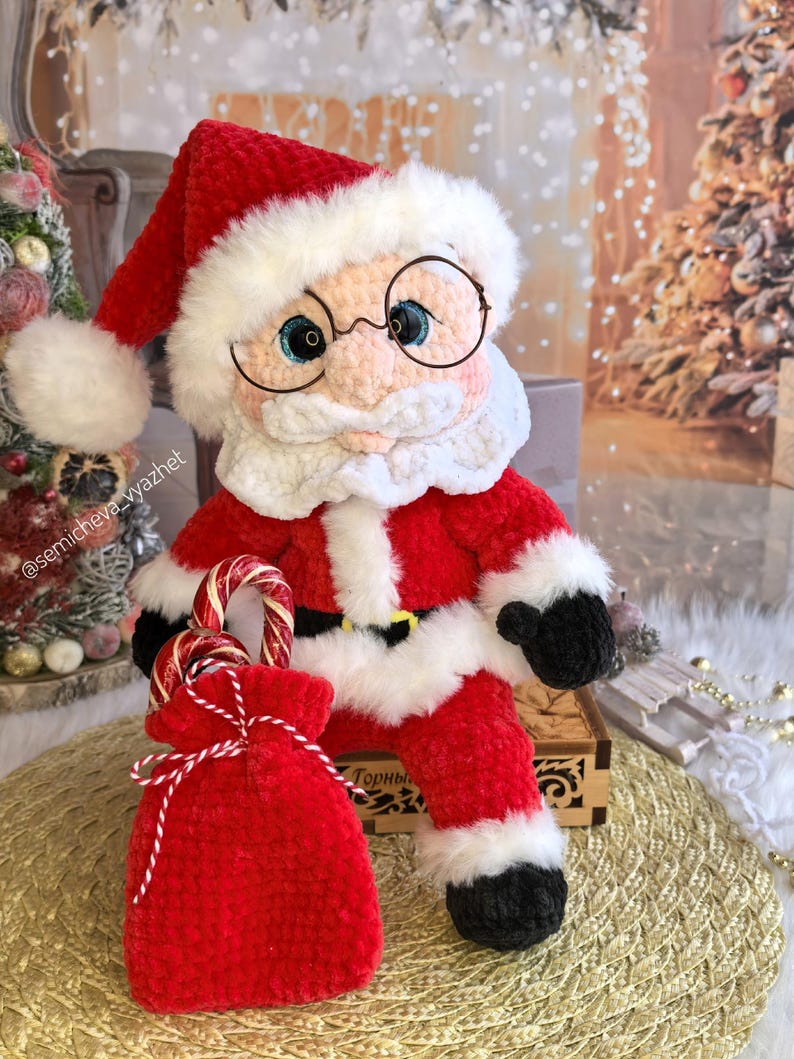 Pode incluir: Boneca de Papai Noel de pel&uacute;cia feita &agrave; m&atilde;o, vestindo um terno vermelho com acabamento branco, botas pretas e um chap&eacute;u combinando. A boneca tem &oacute;culos redondos e segura uma sacola vermelha com bengalas doces. Uma decora&ccedil;&atilde;o de Natal festiva.