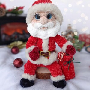 Pode incluir: Boneca artesanal do Papai Noel, feita de tecido de pel&uacute;cia vermelho e branco. A boneca apresenta barba branca, &oacute;culos redondos e um chap&eacute;u vermelho. Segura um saco vermelho com bengalas doces, perfeito para o Natal.