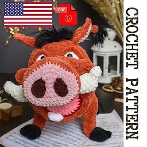 Puede incluir: Un juguete de jabalí tejido a mano en naranja, rosa y blanco, con detalles en negro. El texto "CROCHET PATTERN" se muestra verticalmente. Una bandera estadounidense y un icono de descarga PDF están en la parte superior izquierda.