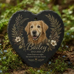 Puede incluir: Una placa conmemorativa de pizarra negra en forma de corazón con el retrato de un golden retriever, ilustraciones florales y el texto: Bailey, 2012-2025, Gone from our sight, but never from our hearts. La placa tiene un orificio superior.