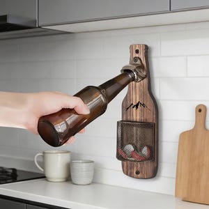 May include: Wooden bottle opener shaped like a bottle, mounted on a white tiled wall. The opener has a metal cap remover and a small wire mesh basket. A brown glass bottle is being opened.
