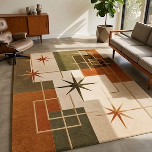 Könnte beinhalten: Ein rechteckiger Teppich mit cremefarbenem Hintergrund und geometrischen Blöcken in Olivgrün und gebranntem Orange. Das Design zeigt mehrere mehrzackige Sternmotive in Orange- und Dunkelgrüntönen, die durch dünne Linien miteinander verbunden sind.