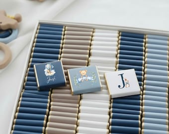 May include: A box of chocolates with a blue, white, and tan color scheme. Some chocolates have illustrations of a teddy bear, a hot air balloon, and a bunny. The name "Jack" is written on one of the chocolates.
