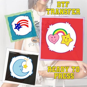 May include: DTF transfer designs featuring cartoon characters. One design has a blue star and red stripes, another has a rainbow, heart, and star, and the last has a blue moon and star. The text "READY TO PRESS" and "DTF TRANSFER" are also visible.