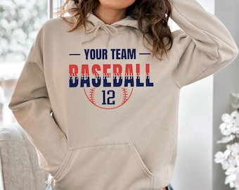 May include: A beige hoodie with a front pocket and a drawstring hood. The front of the hoodie features the text "YOUR TEAM BASEBALL 12" in red and navy blue, with a baseball graphic.