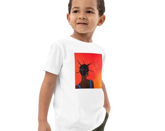 May include: A white short-sleeved t-shirt featuring a square graphic print on the chest. The graphic depicts the back view of a person with dark skin and black hair styled in multiple small, upright braids against a vibrant red and orange background.