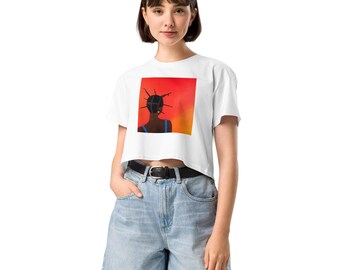 May include: White crop top with a square graphic featuring a silhouette of a person with a unique hairstyle against a red and orange background. The person is wearing a blue top. The shirt has short sleeves and a crew neck.
