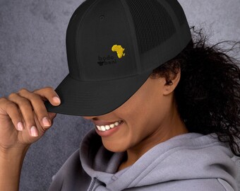 May include: Black trucker hat with a mesh back and a curved brim. The hat features the embroidered text "bodo bani" in black and a gold outline of the African continent. A stylish accessory.