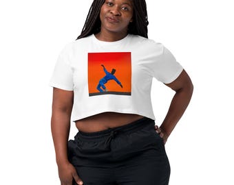 May include: White crop top featuring a vibrant square graphic of a person in a blue outfit against an orange and red background. The top is paired with black athletic pants.