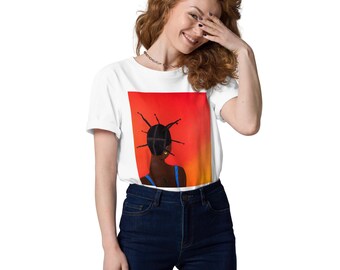 May include: White t-shirt featuring a vibrant artwork of a person with dark skin, styled hair, and a blue top against a red and orange gradient background. The person is facing away from the viewer. The model is wearing dark blue jeans.