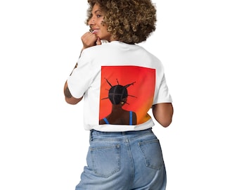 May include: White t-shirt featuring a vibrant graphic on the back. The artwork depicts a woman with dark skin and a unique hairstyle, set against a red and orange gradient background. The woman is wearing a blue top.