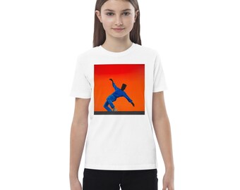 May include: White t-shirt featuring a vibrant graphic of a person in a blue outfit dancing against a red and orange background. The design is centered on the shirt, creating a bold visual statement. The shirt is made of a soft material.