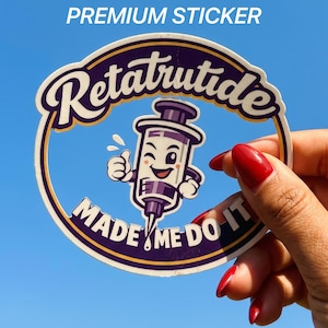 May include: A round sticker with a dark purple border and a light blue center. It features a cartoon syringe character winking and giving a thumbs up. The text reads Retatrutide at the top and MADE ME DO IT at the bottom in white lettering.