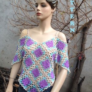 Pode incluir: Um top de croch&ecirc; com um padr&atilde;o floral roxo e azul. O top tem um decote em V e &eacute; sem mangas. A modelo est&aacute; usando jeans azul. O texto "PATTERN" est&aacute; escrito verticalmente no lado direito da imagem. O texto "www.etsy.com/shop/natyo2010" est&aacute; na parte inferior da imagem.