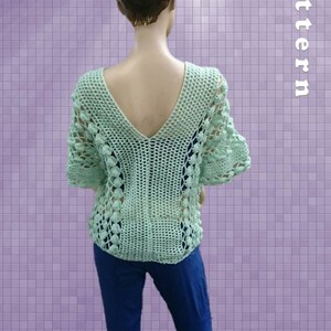 Peut inclure: Un haut en crochet vert clair avec un col en V et des manches courtes. Le haut a un motif en dentelle et est pr&eacute;sent&eacute; sur un mannequin.