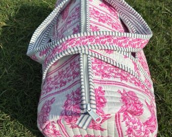 Pode incluir: Mala de viagem acolchoada com um padrão floral rosa e branco. A mala tem um zíper cinza e alças listradas. É feita de um material acolchoado macio, adequado para viagens ou uso diário.