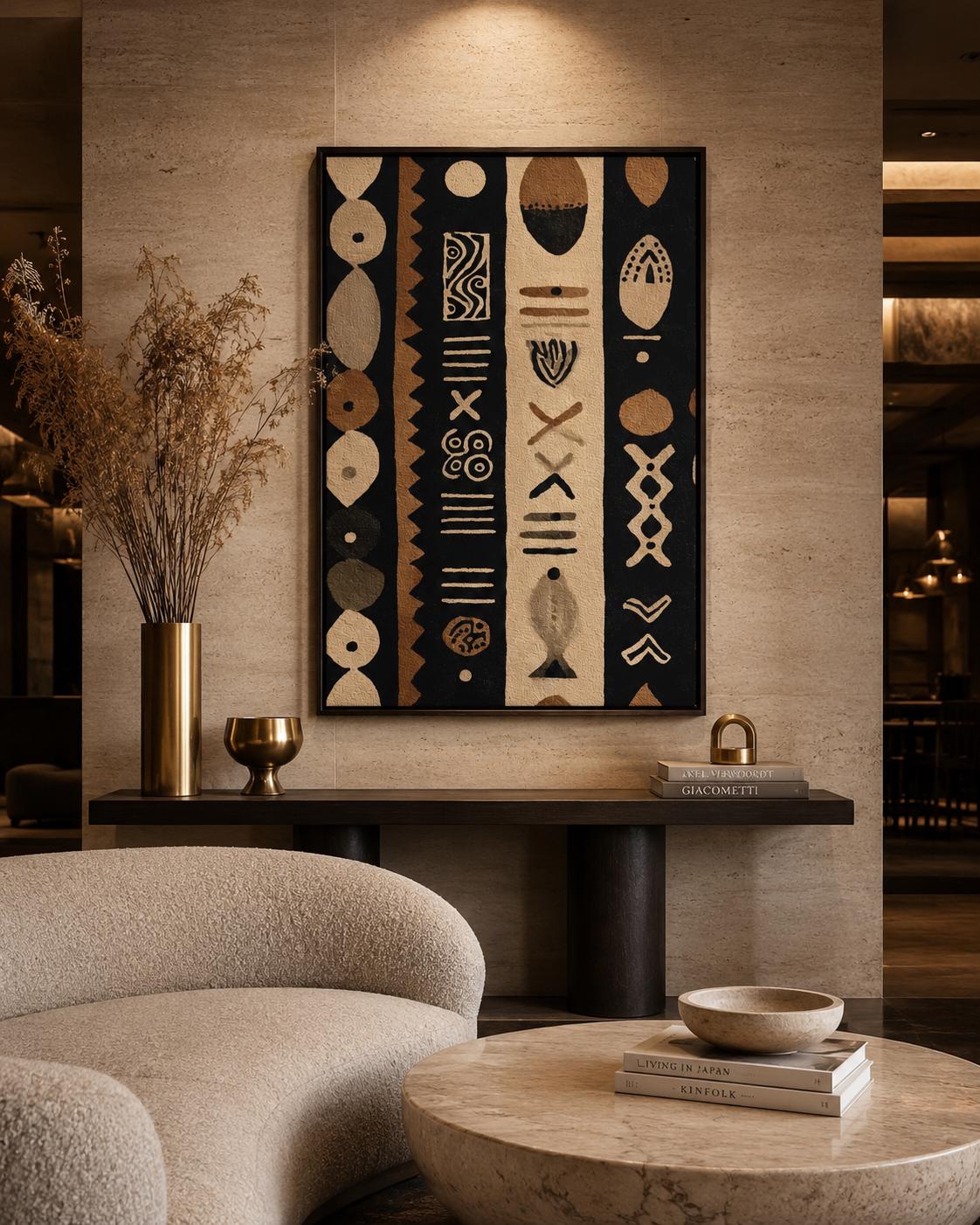Man standing near a wall holding a drink next to a framed geometric tribal pattern artwork