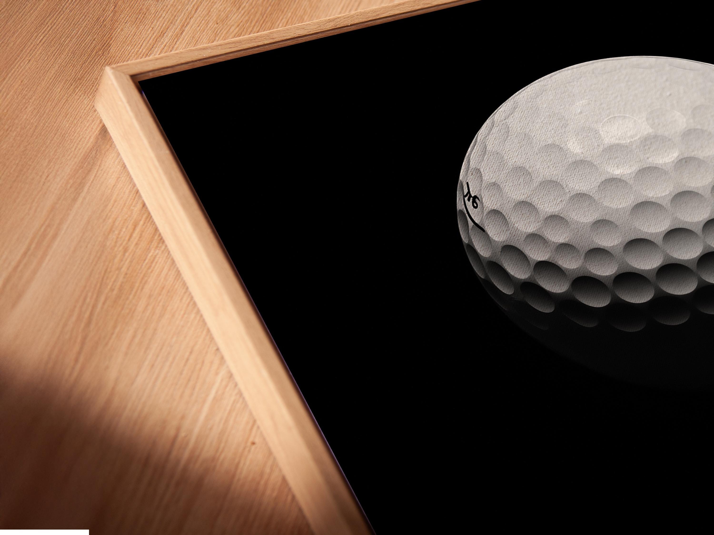 Minimalist golf ball design on a black background with a vivid red vertical accent detail view