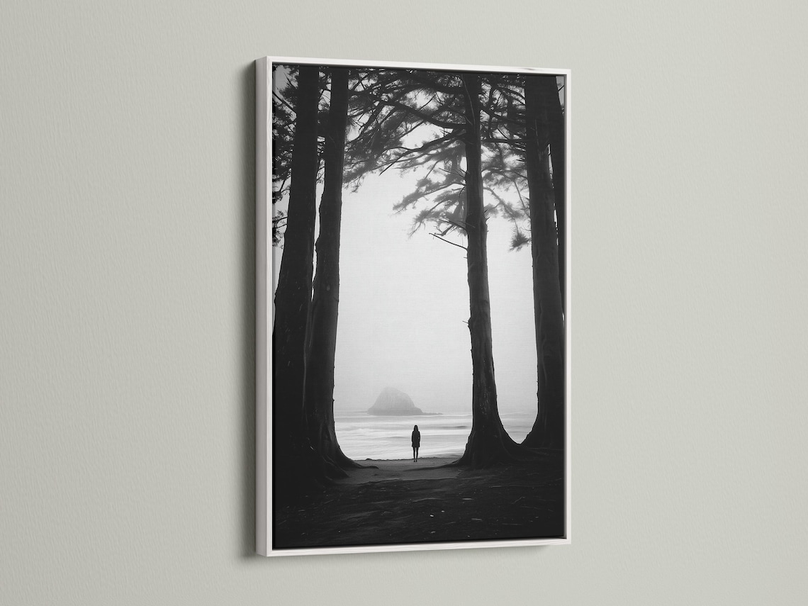Monochrome seascape with dark tree trunks framing a foggy beach and a small lone figure detail view