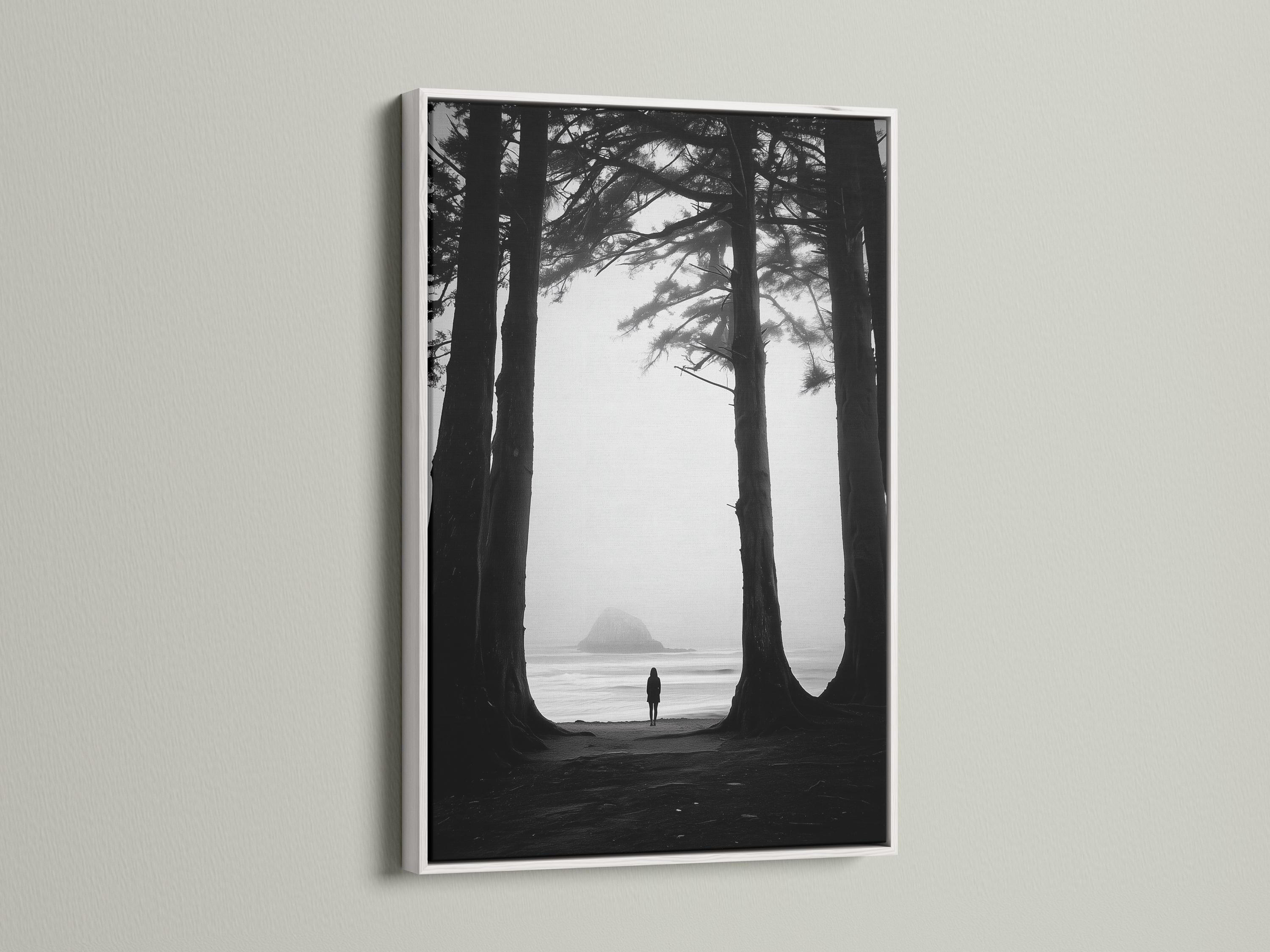 Monochrome seascape with dark tree trunks framing a foggy beach and a small lone figure detail view