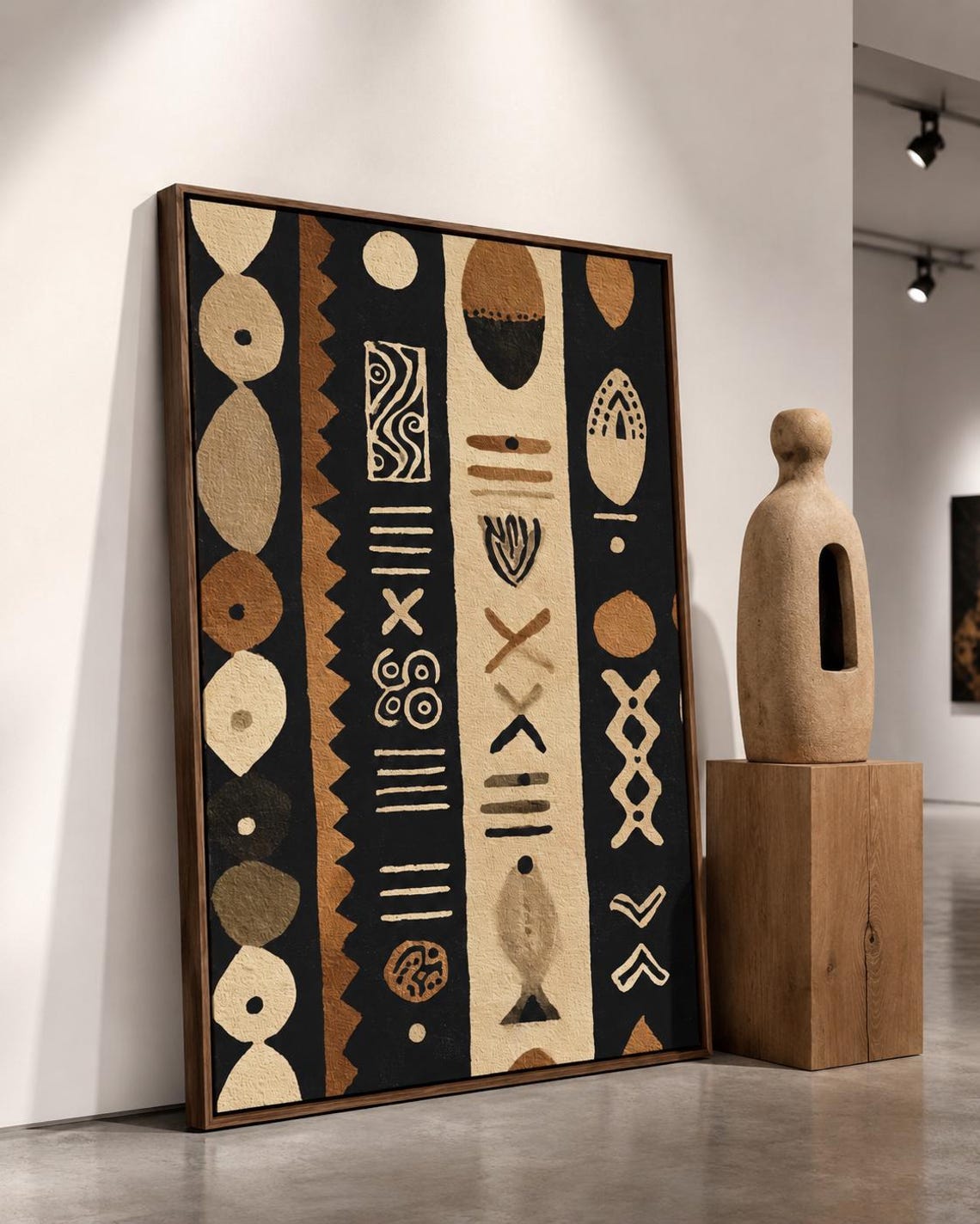 Man standing near a wall holding a drink next to a framed geometric tribal pattern artwork
