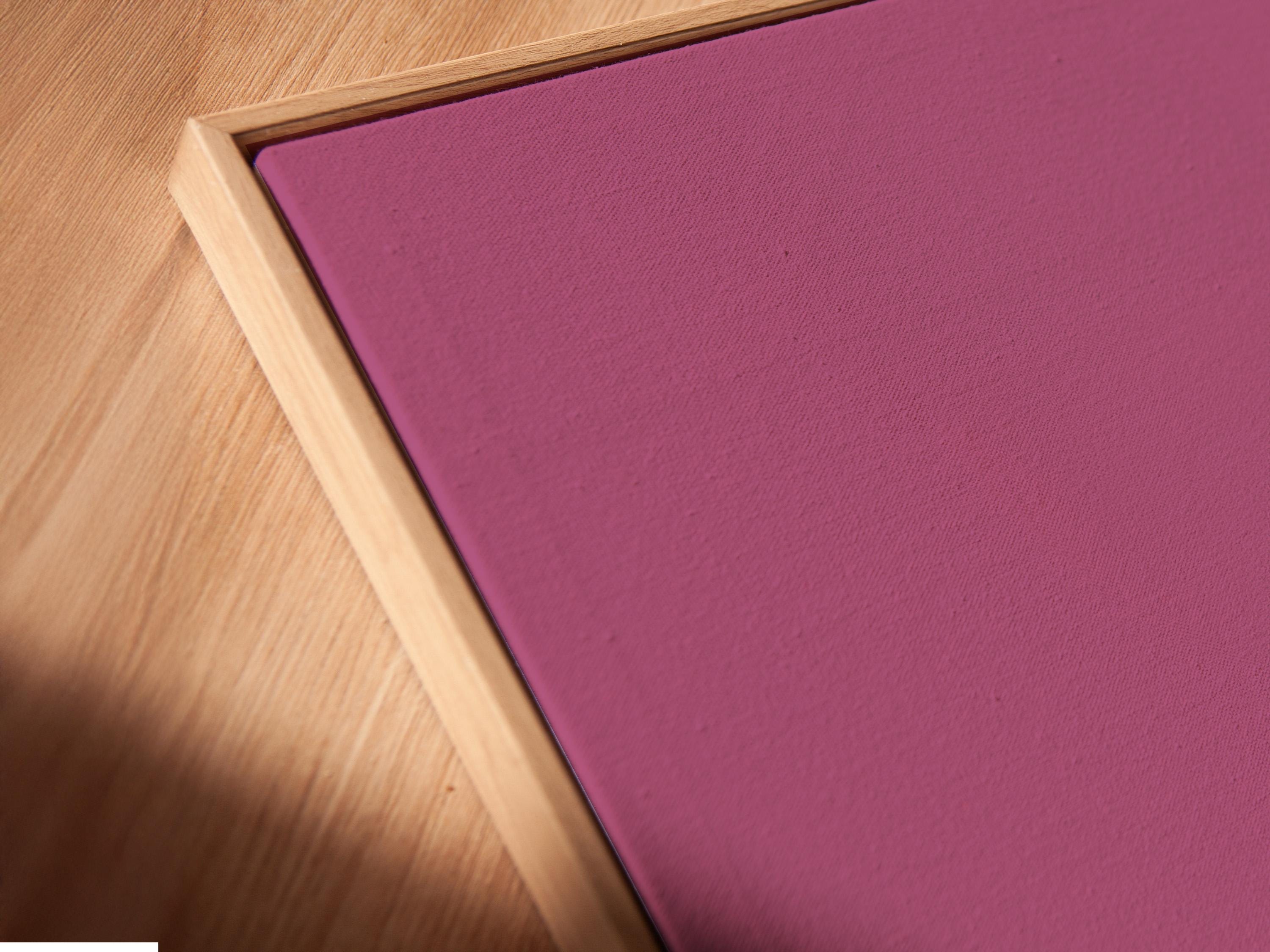 Mockup showing a framed pink minimalist traveller figure artwork on a light background