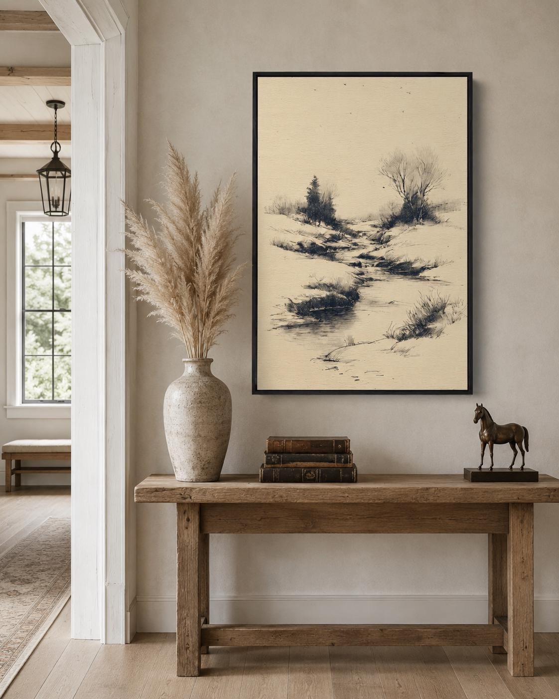 Woman holding a large framed beige river landscape sketch on a light wall in a bright room