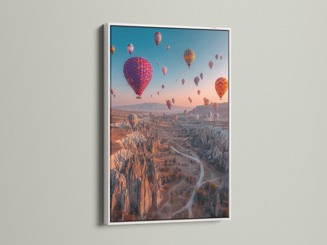 A dusk landscape with multiple colourful hot air balloons in the sky over a rocky valley detail view