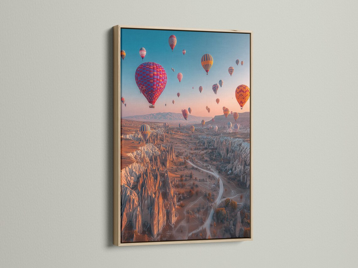 A dusk landscape with multiple colourful hot air balloons in the sky over a rocky valley detail view