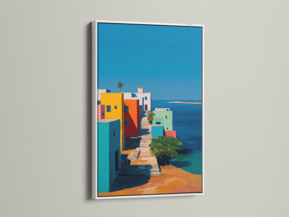 Wall mockup showing a framed coastal village artwork with colourful buildings and blue sky