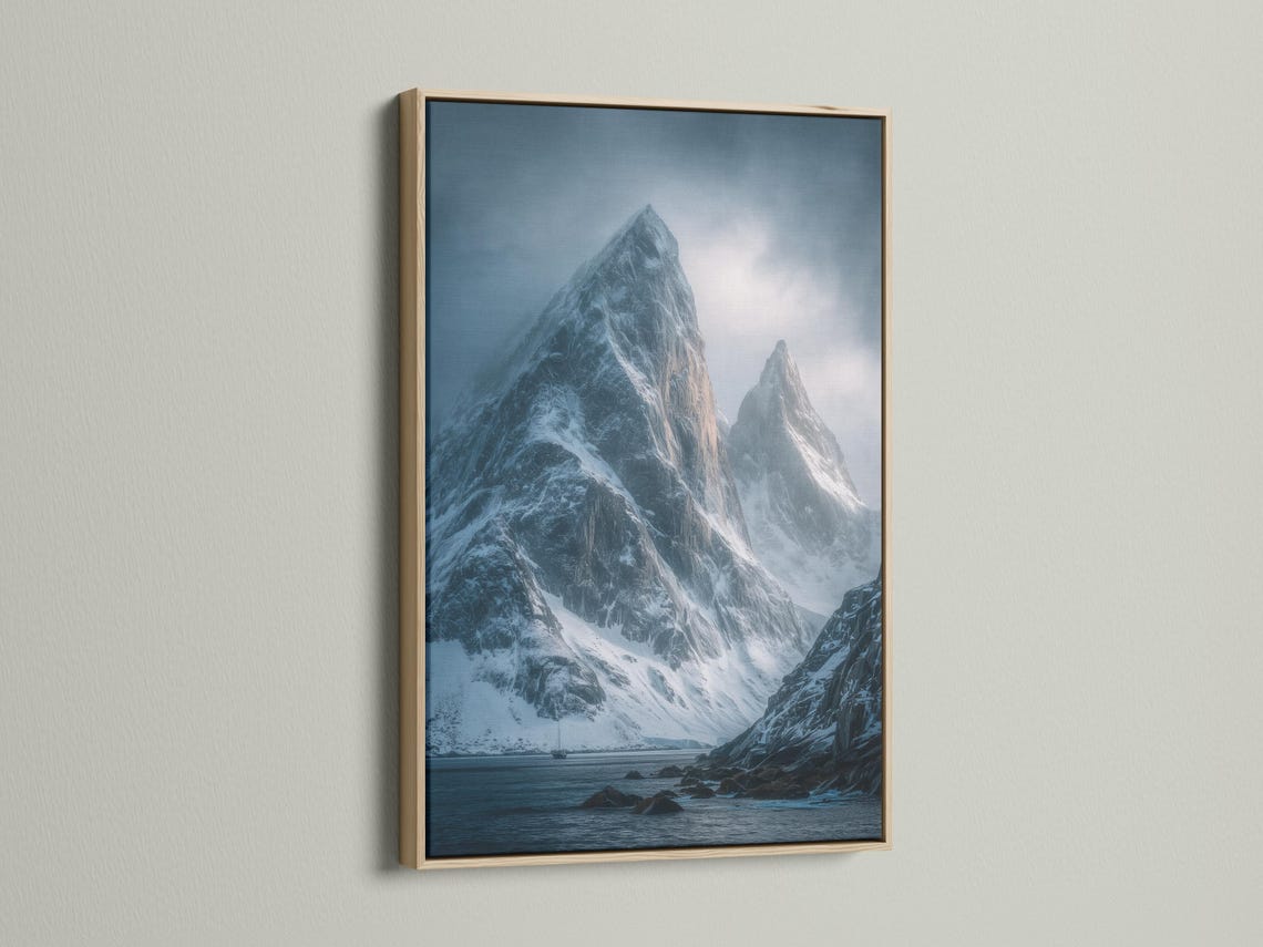 Blue misty mountain landscape with snow peaks, cloudy sky, and dark rocky shoreline detail view