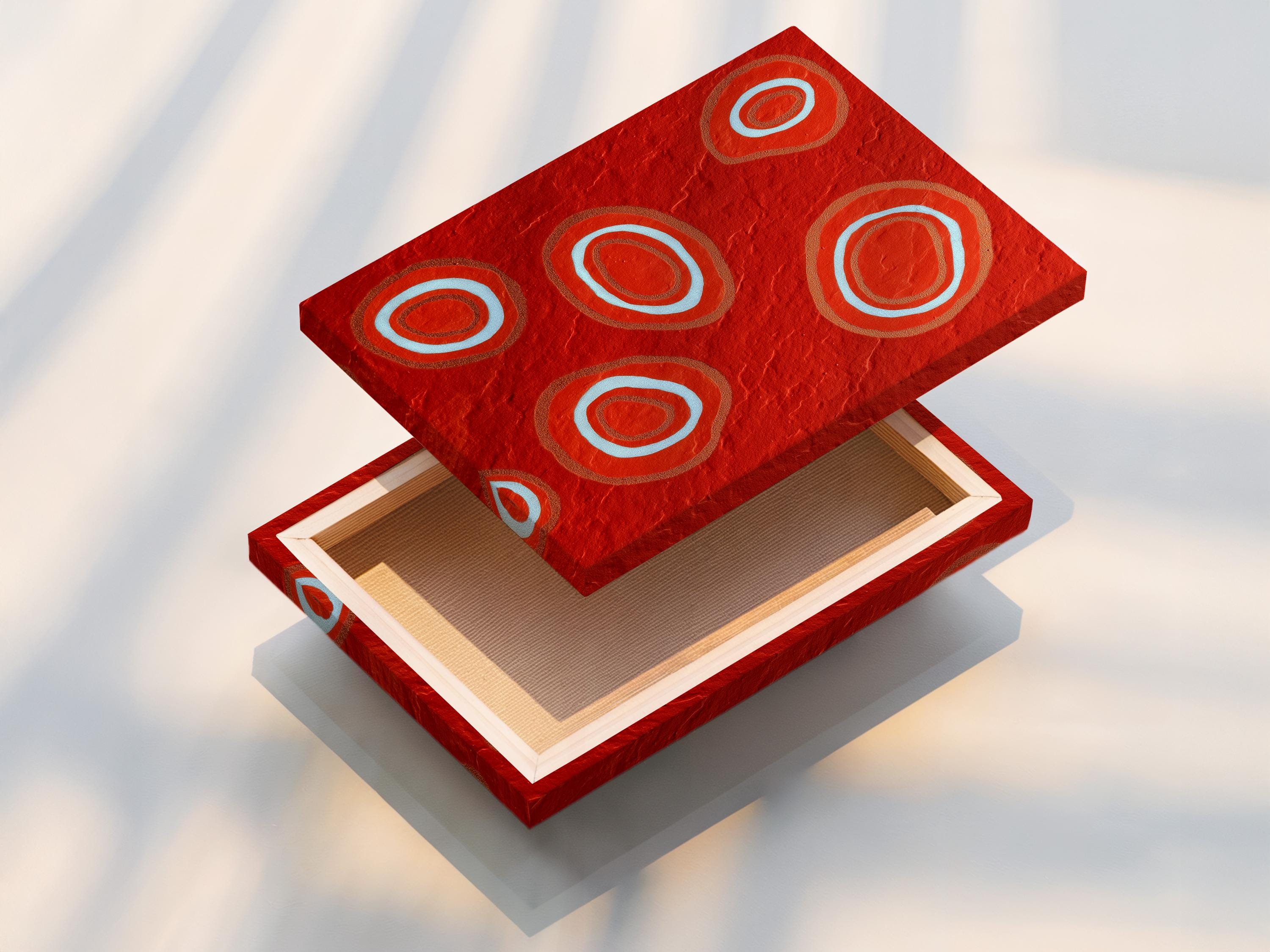 Room mockup showing a red abstract artwork with concentric circle motifs in pale blue and copper tones