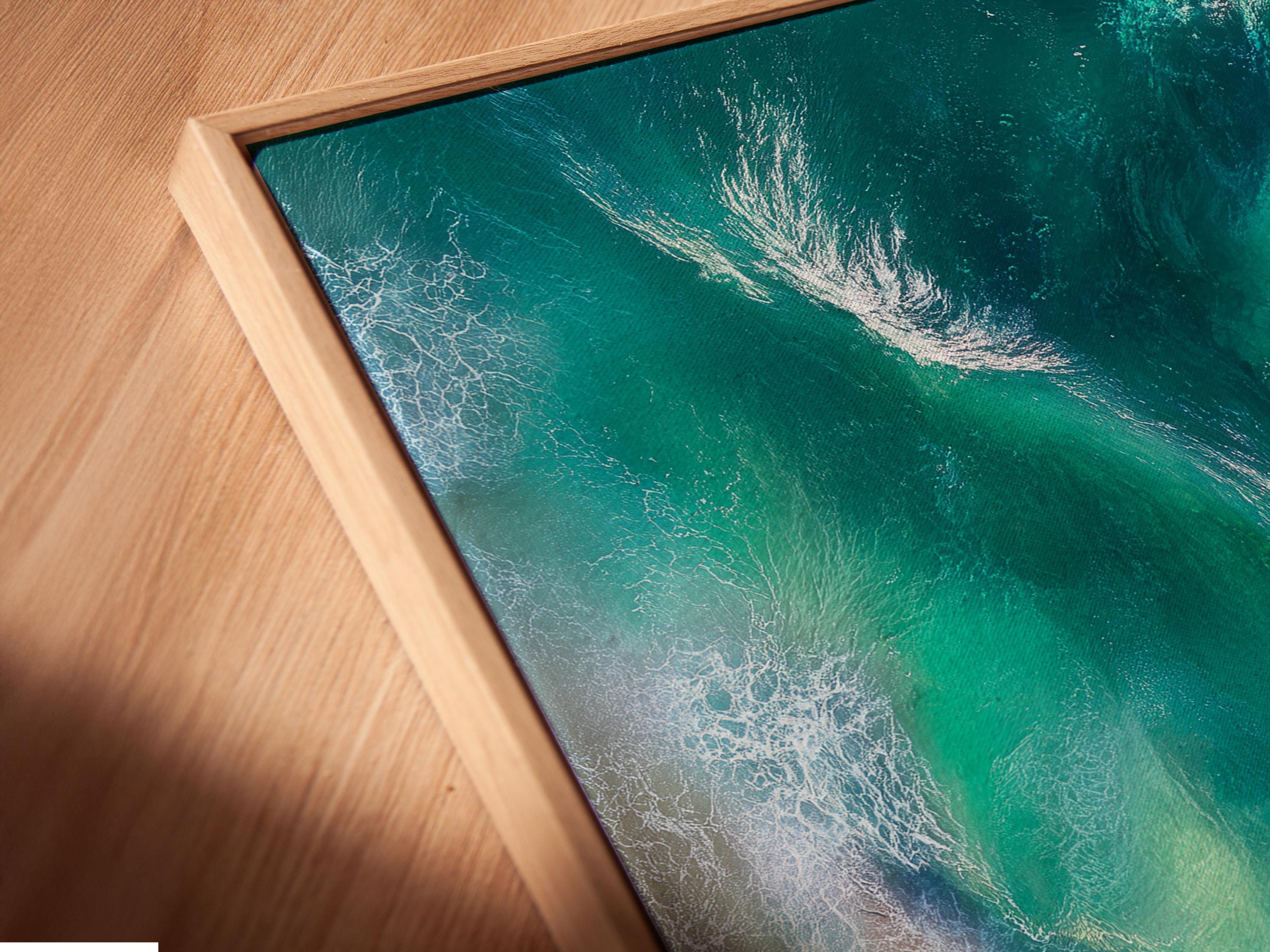 Aerial view of turquoise ocean waves with white foam meeting a sandy beach detail view