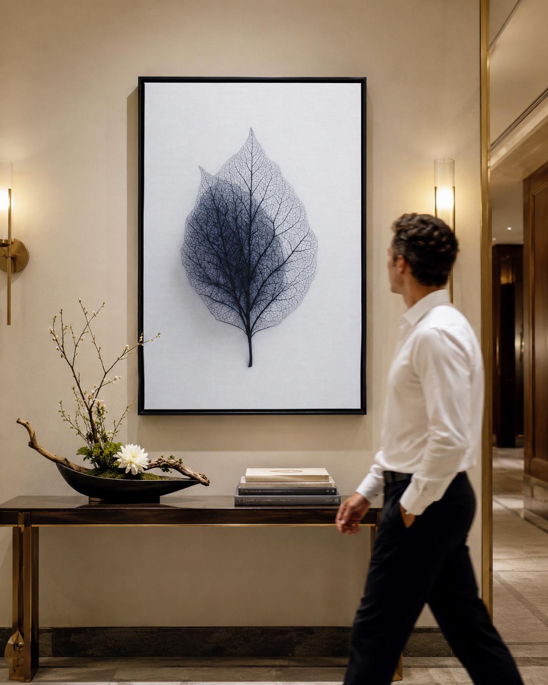 A person looking at a framed leaf skeleton wall artwork in a bright room