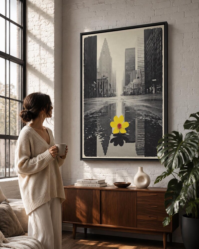 A monochrome city skyline is overlaid with a single bright yellow flower, reflected in water-like bands, creating a high-contrast urban accent