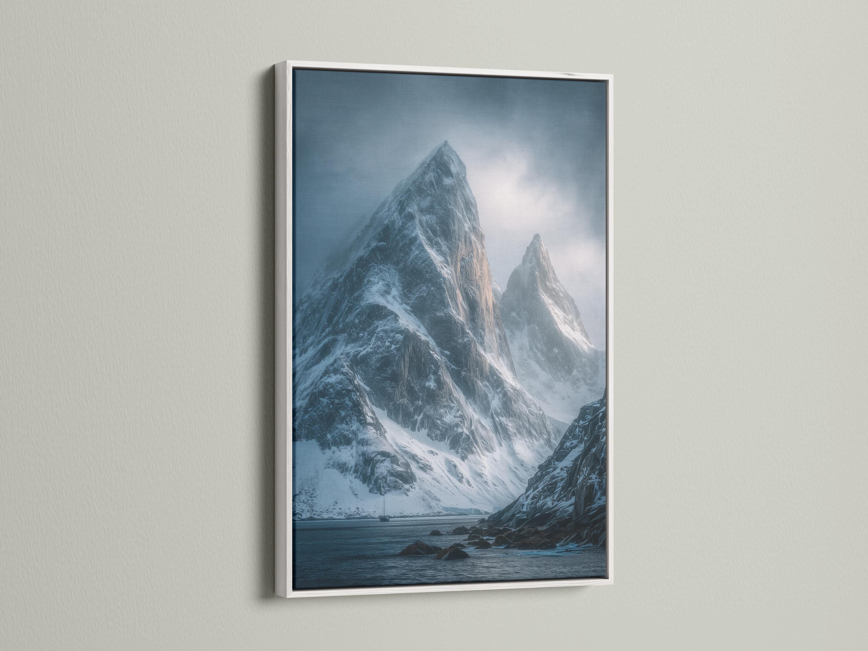 Blue misty mountain landscape with snow peaks, cloudy sky, and dark rocky shoreline detail view