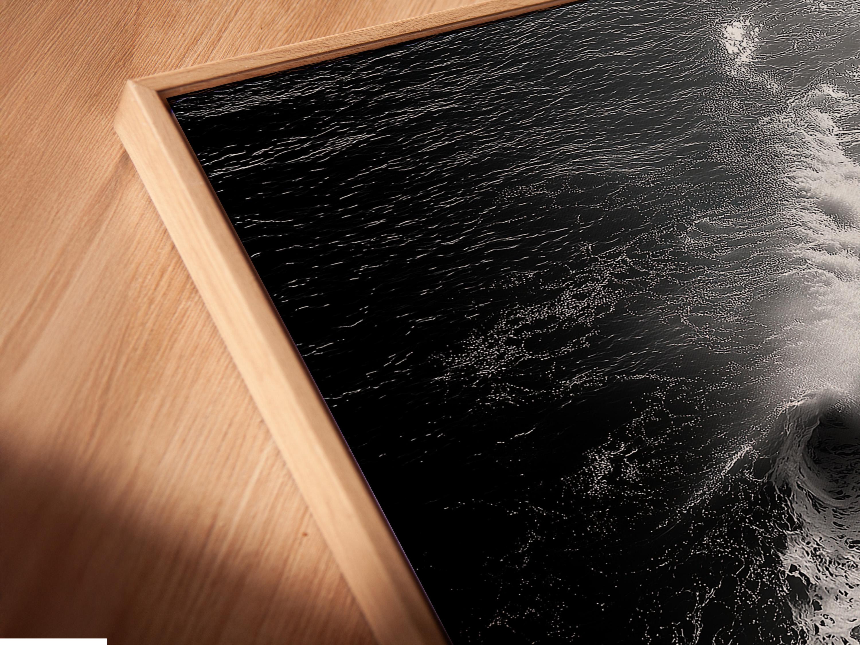 A monochrome seascape shows a foamy wave curling in bright white against deep black water, with a high-contrast, textured finish detail view