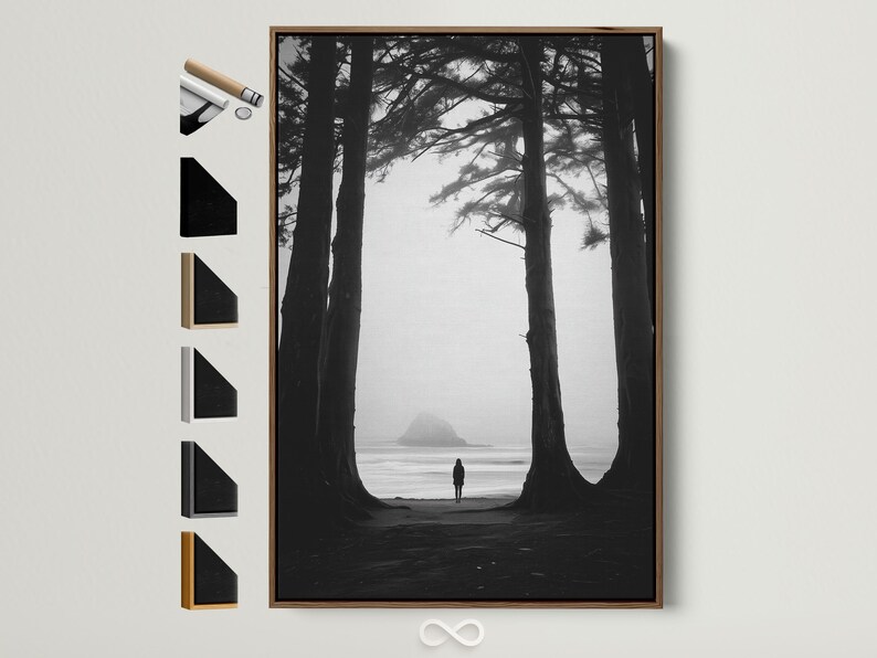 Monochrome seascape with dark tree trunks framing a foggy beach and a small lone figure