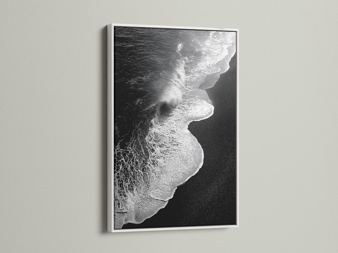 A monochrome seascape shows a foamy wave curling in bright white against deep black water, with a high-contrast, textured finish detail view