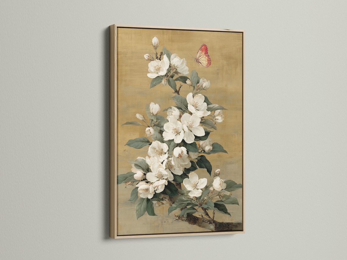 Vertical framed artwork mockup on a light wall with a bouquet of white blossoms and a butterfly