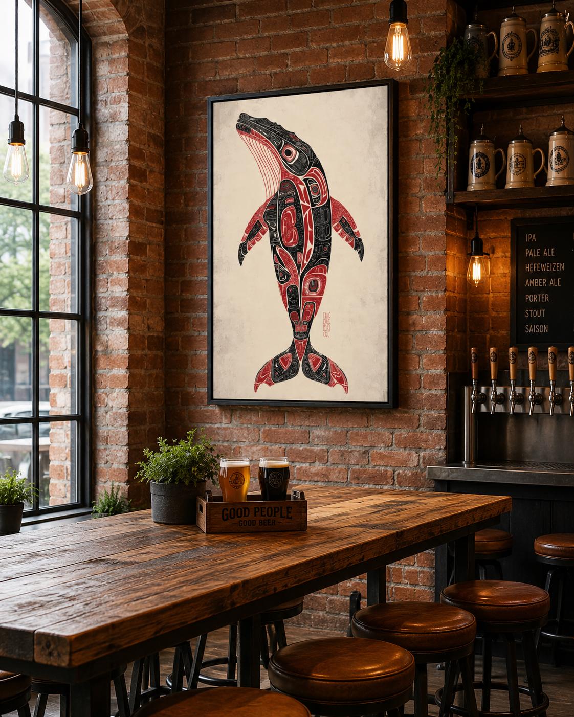 Man holding a mug beside a framed whale artwork in a rustic cabin setting