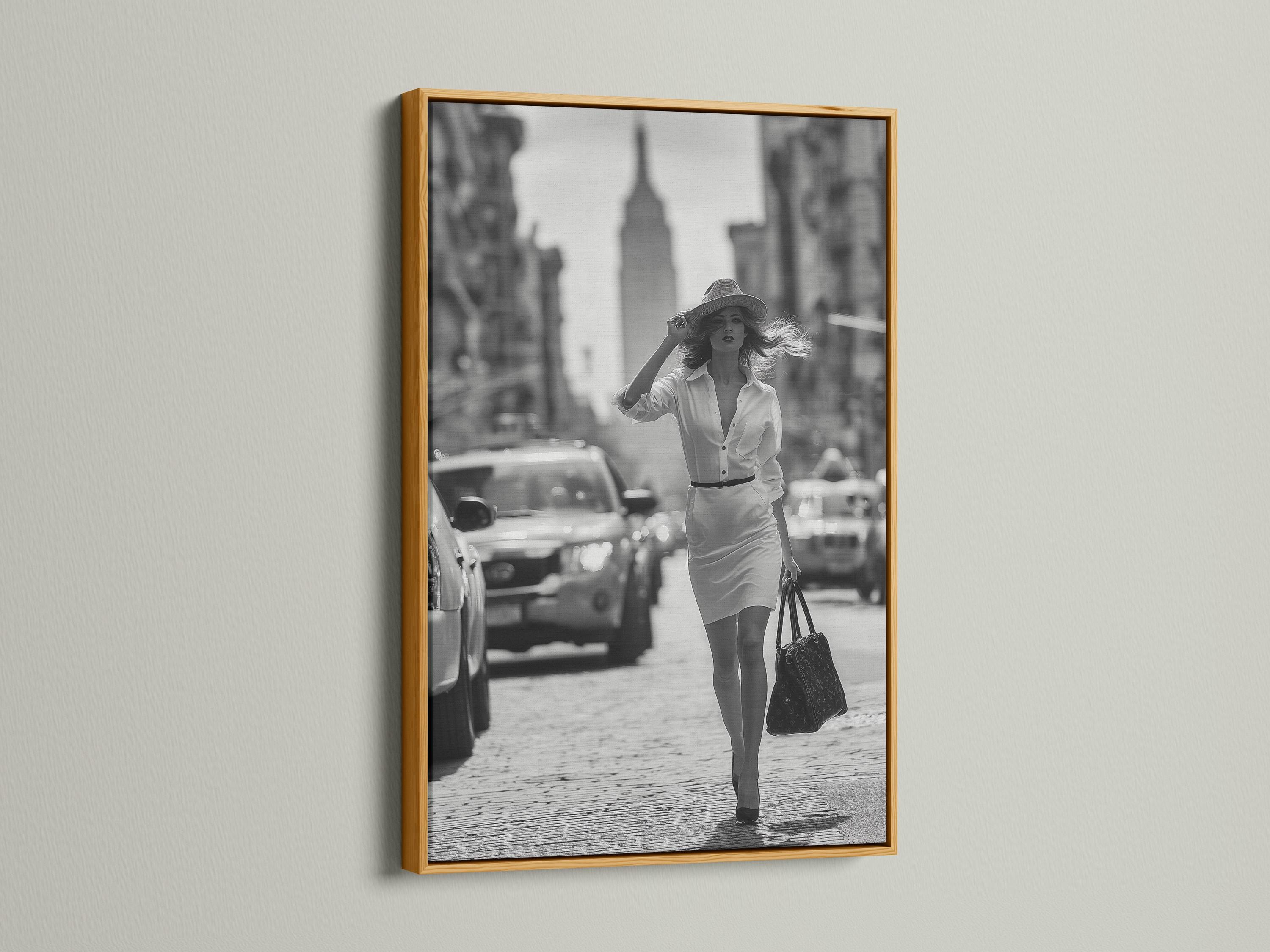 A black-and-white street photograph shows a stylish woman walking forward with a hat and handbag, with blurred city buildings and cars behind her