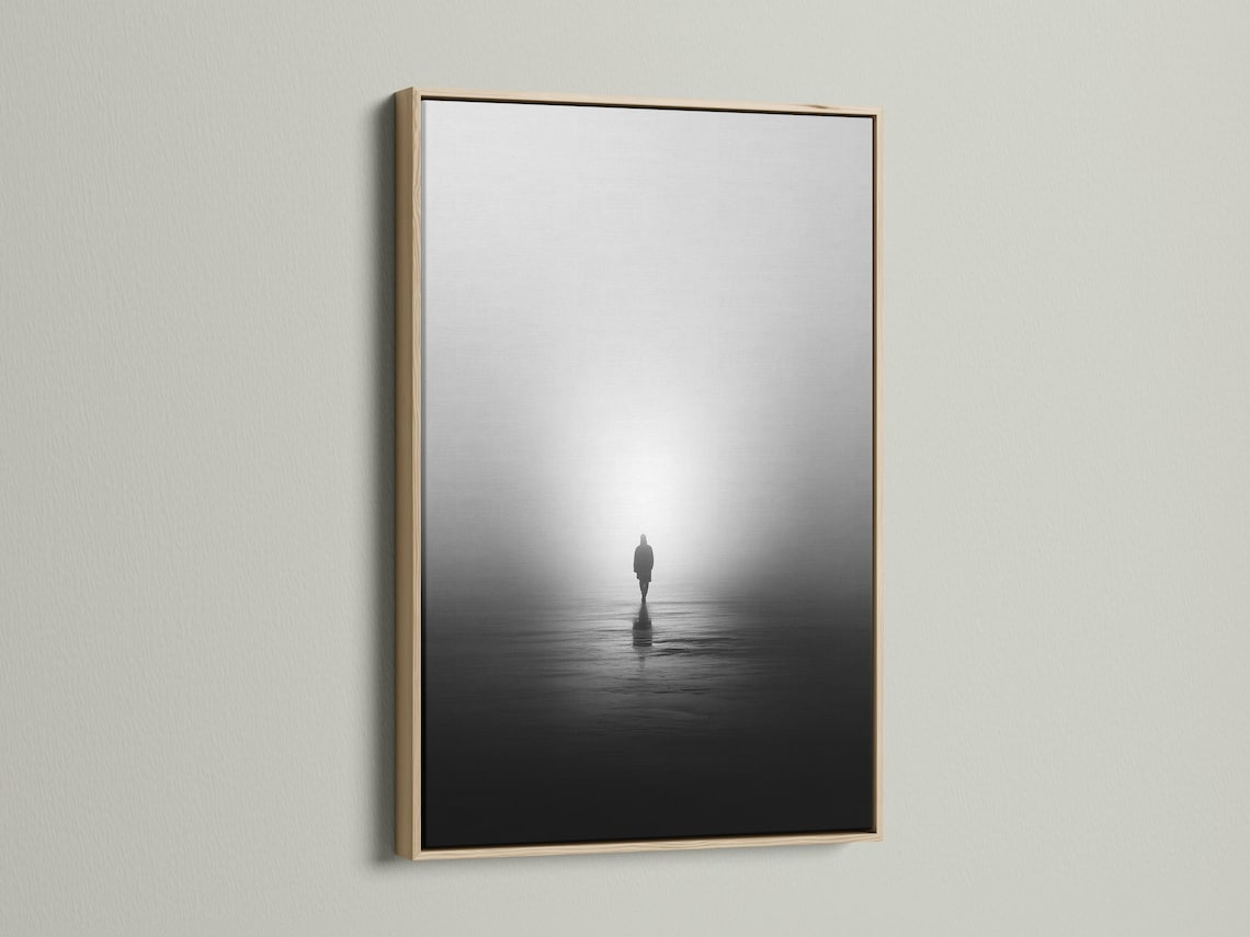Monochrome misty shore scene with a solitary standing figure and reflection on dark water detail view