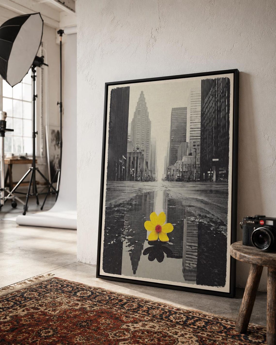 A monochrome city skyline is overlaid with a single bright yellow flower, reflected in water-like bands, creating a high-contrast urban accent detail