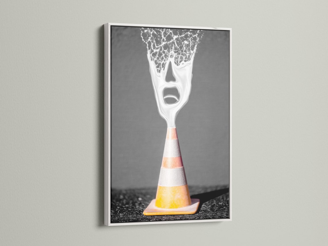 A surreal traffic cone stands on dark ground, its top appearing as a screaming white face with high-contrast, graphic detailing detail view