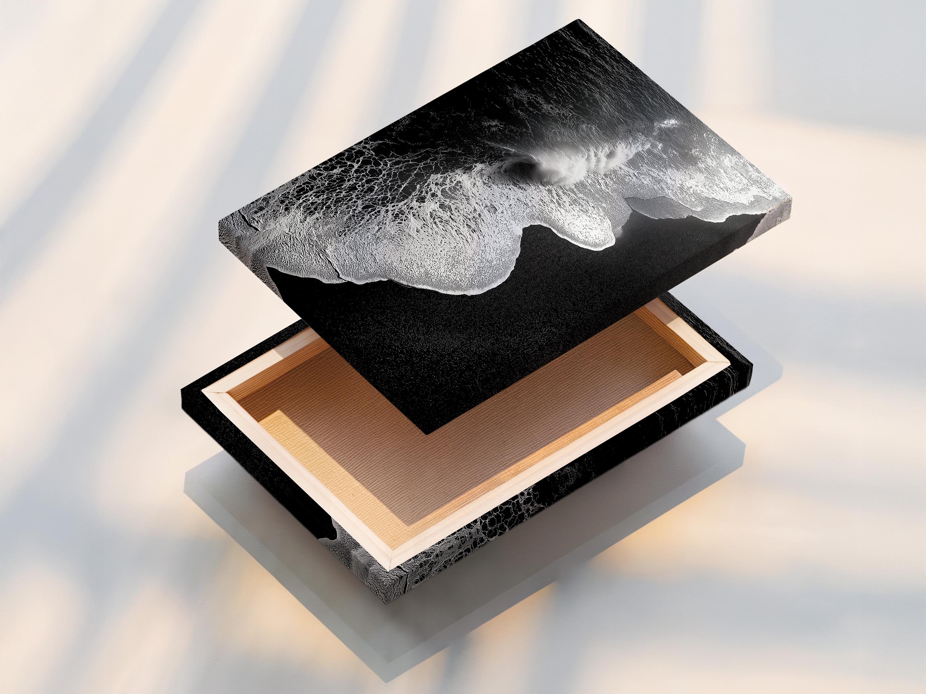 A monochrome seascape shows a foamy wave curling in bright white against deep black water, with a high-contrast, textured finish detail view