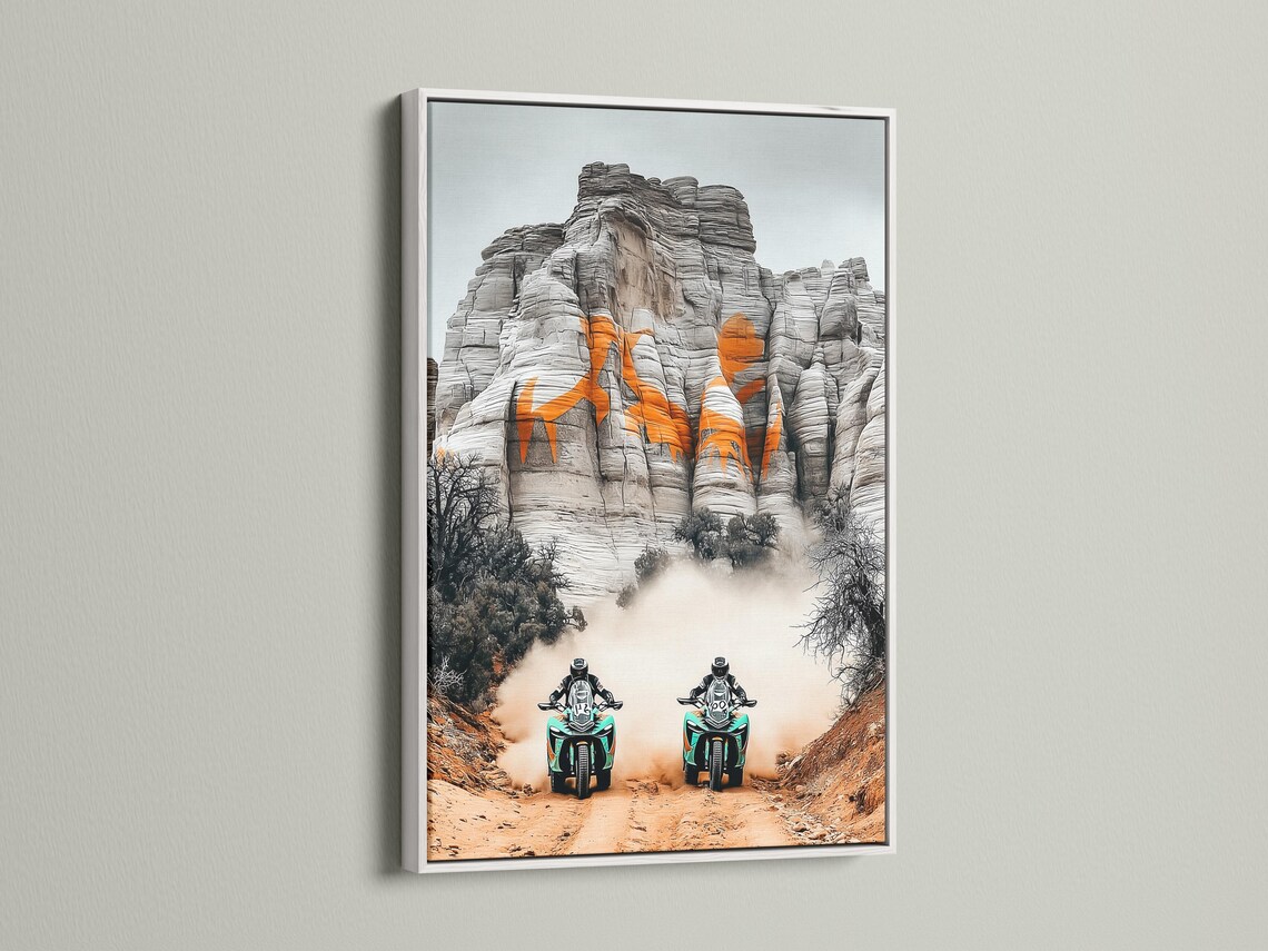 Two off-road motorcycles with turquoise accents racing through desert haze against grey cliffs detail view